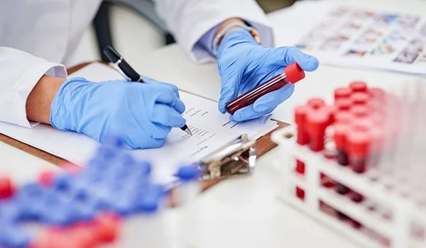 A healthcare professional recording details for a blood sample